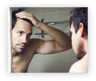 Muž sleduje v zrcadle účinky Minoxidilu